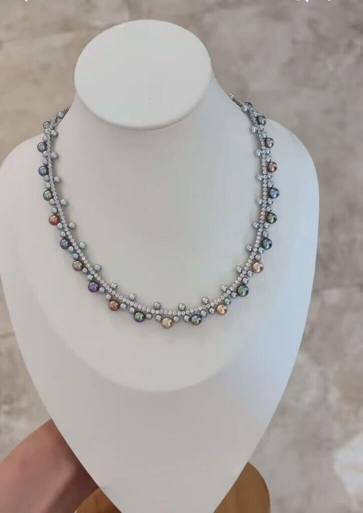 Close-up of hand-attached mixed-size pearl clusters along a stone-set chain.