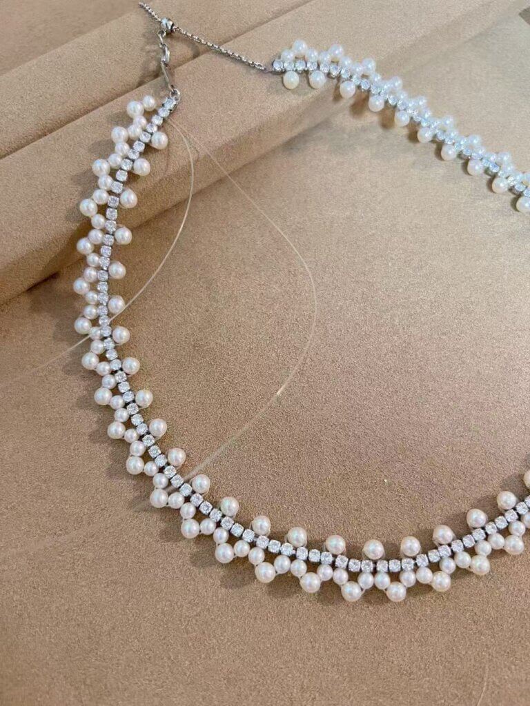 Pearl cluster necklace layout being adjusted by hand before final assembly